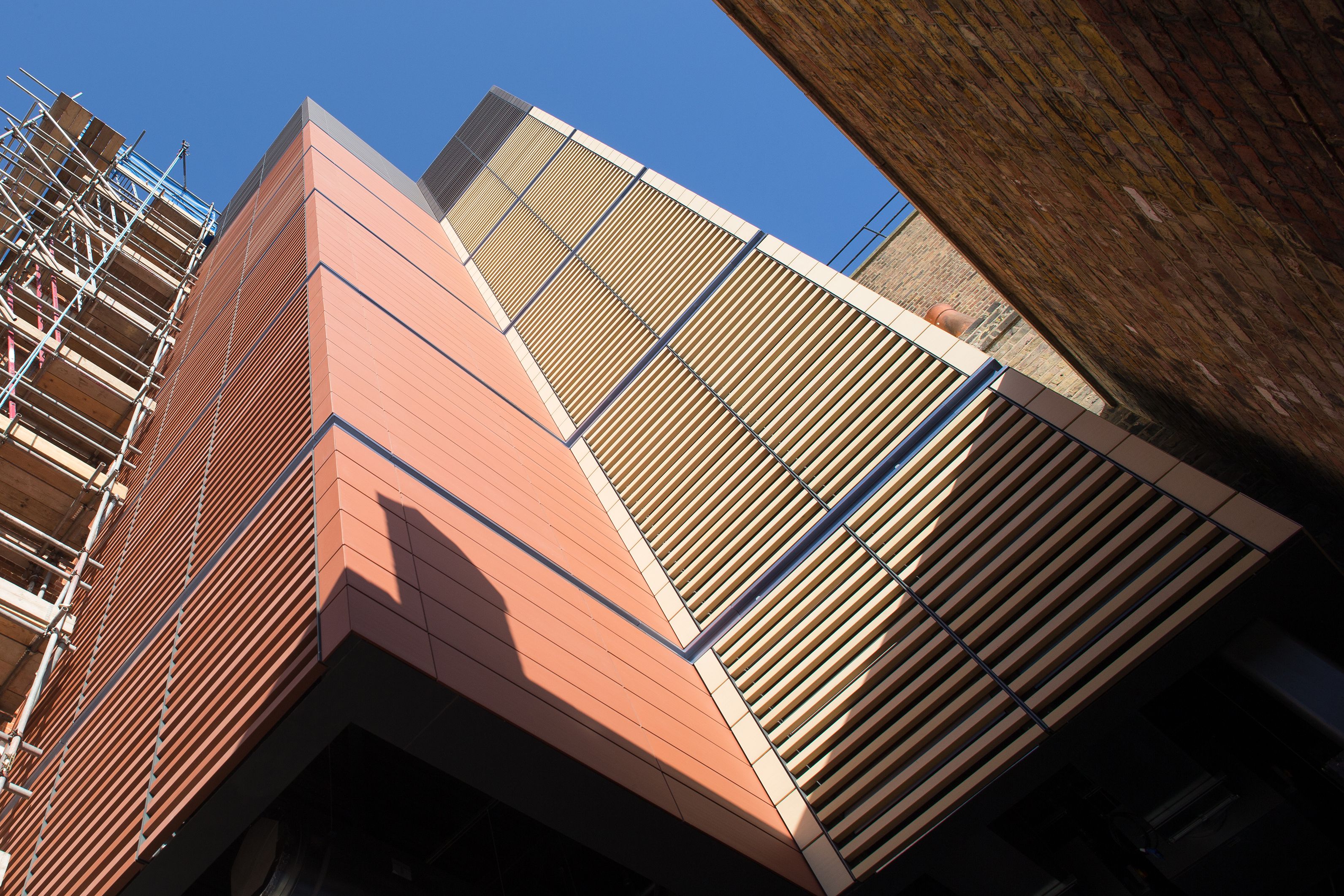 Bottom-up view of a yellow and orange facade of a newly built medical facility